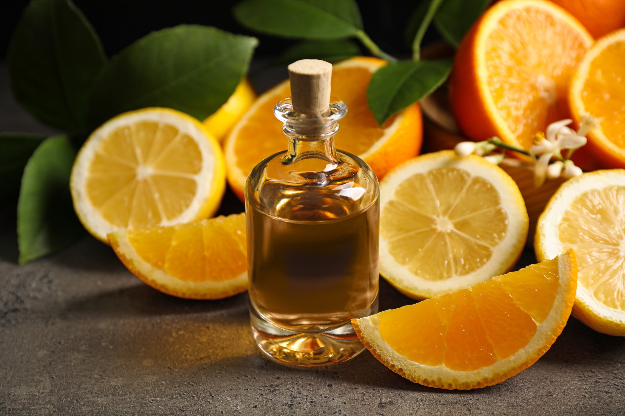 Bottle of Essential Oil and Citrus Fruits on Grey Table